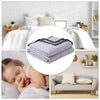 A stack of light purple breathable cooling throw blankets on a bed with a sleeping child.