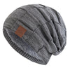 A gray knit beanie with a folded cuff and a brown tag is shown from above.