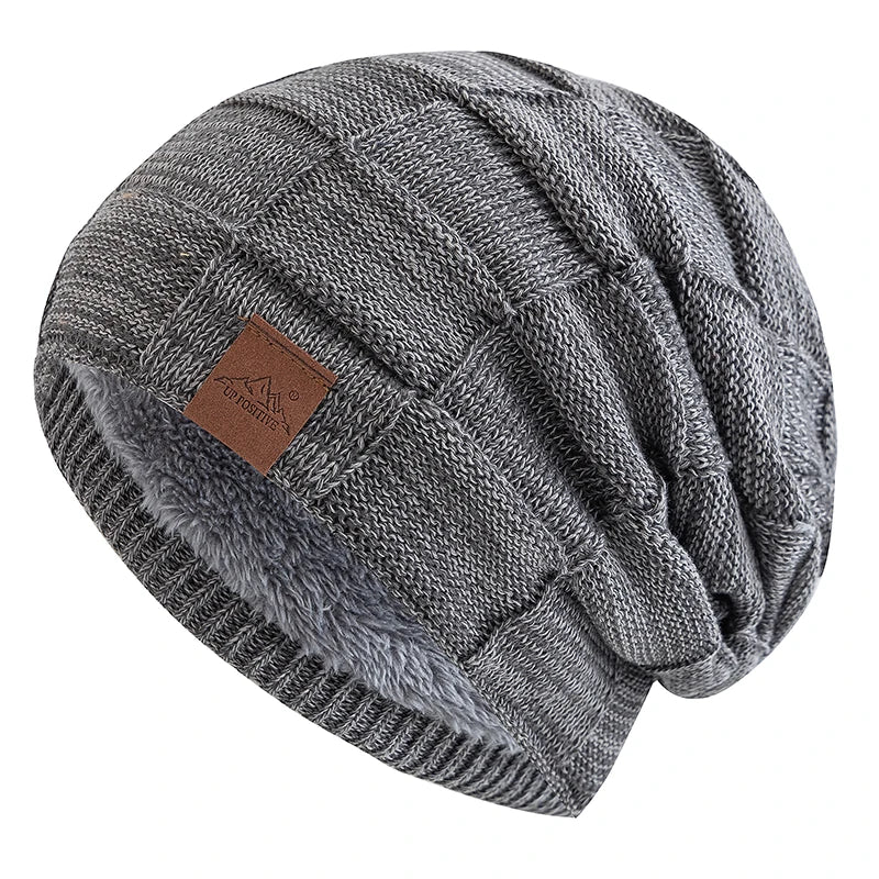 A gray knit beanie with a folded cuff and a brown tag is shown from above.