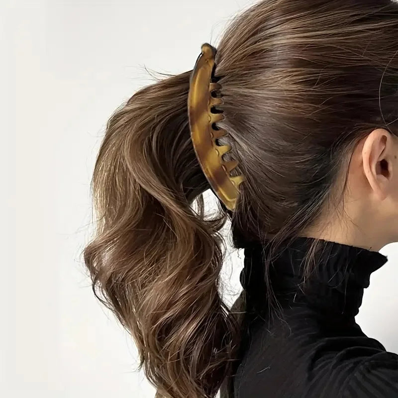 Primer plano del cabello de una mujer en cola de caballo con una pinza de acrílico dorado escarchado.