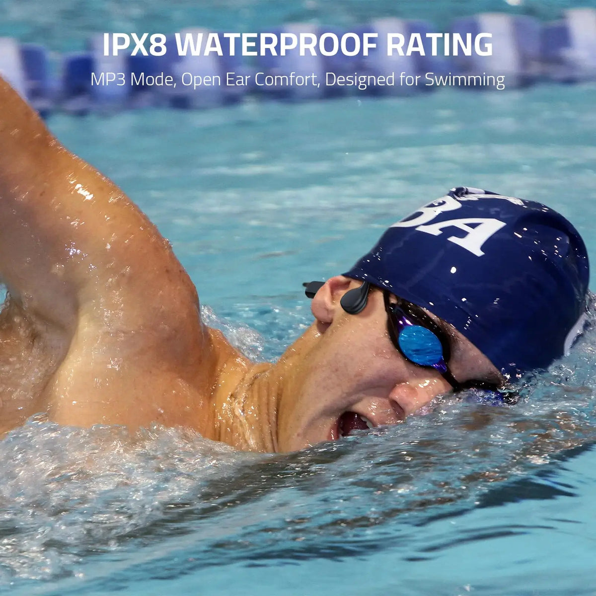 A swimmer wearing a dark blue cap and goggles is submerged in water, demonstrating the IPX8 waterproof rating of sports headp