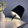 A black LED table lamp with a silver accent is shown illuminating a piece of paper.
