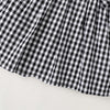 A black and white plaid cotton knit dress with a bow accent shown from the front.