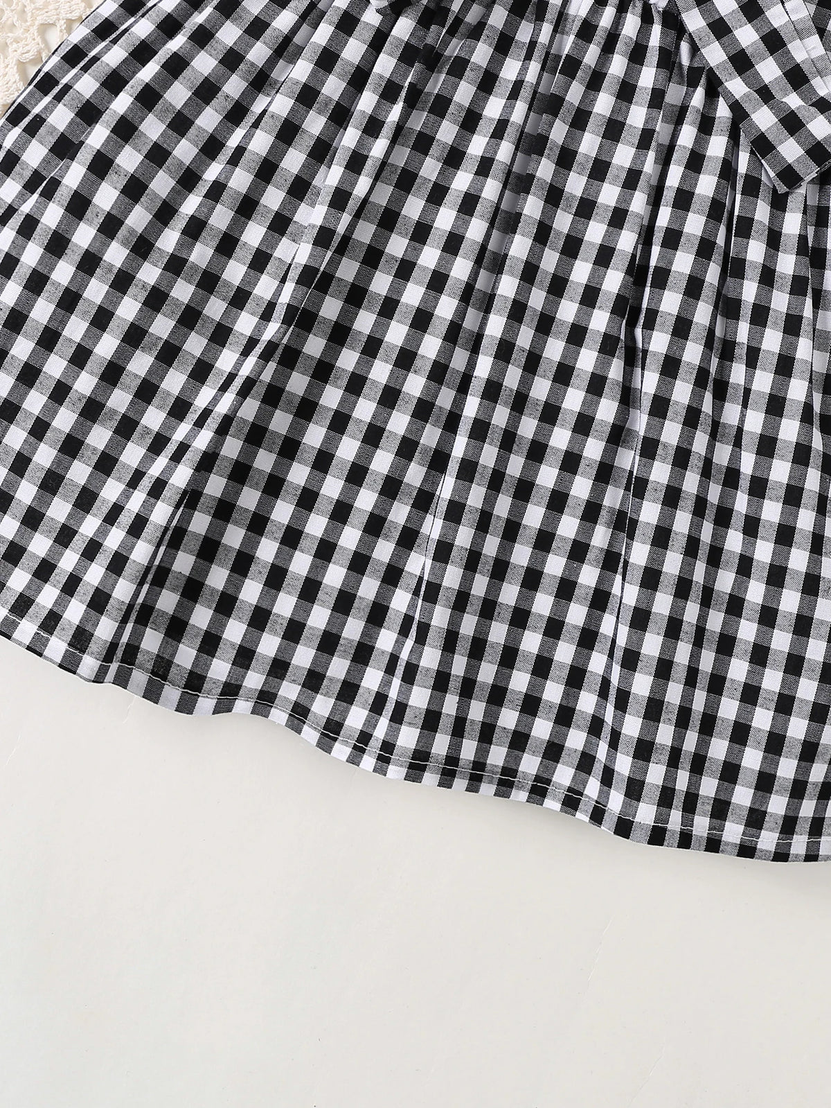 A black and white plaid cotton knit dress with a bow accent shown from the front.