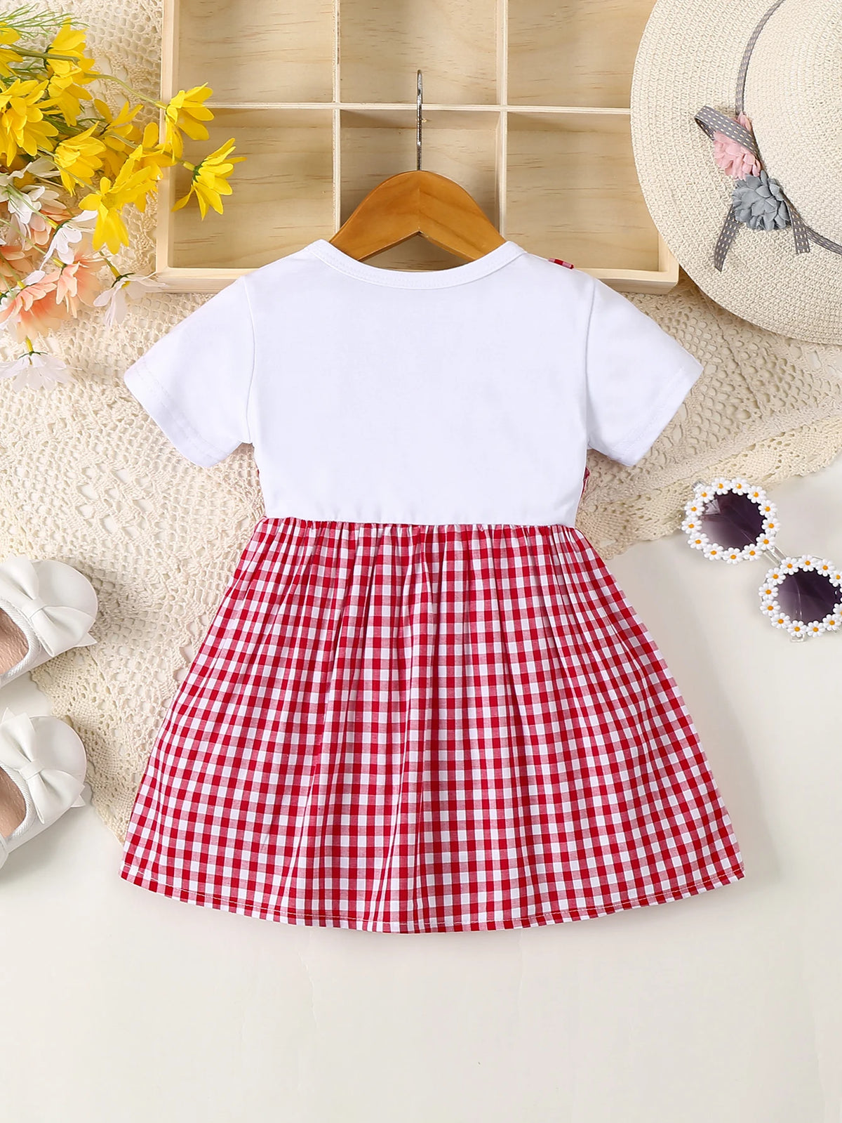 A white long-sleeved cotton knit top paired with a red and white plaid pleated skirt for a girl's dress.