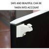 A close-up view of a white magnetic cabinet safety lock being installed on a black cabinet door.