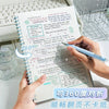 A hand is writing in a spiral notebook with notes and a pen, showing the 360 degree view of the pages.