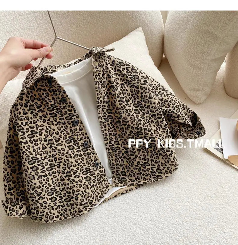 A leopard print denim jacket displayed on a hanger against a light background.