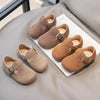 A collection of tan suede non-slip kids' moccasin shoes with hook-and-loop closures displayed on a light gray surface.