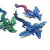 Tres figuritas de dragón articulado impresas en 3D, en verde, rojo y azul.