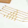 Varios brazaletes de acero inoxidable bañados en oro con cadenas ajustables sobre una superficie blanca.