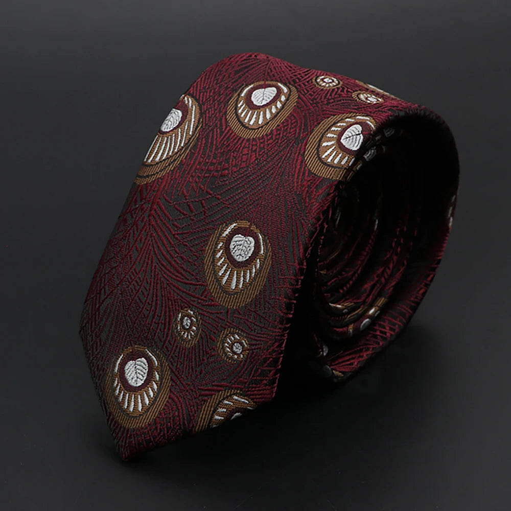 Corbata jacquard rojo oscuro con patrón floral en dorado claro, enrollada sobre fondo oscuro
