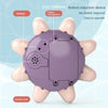 A purple, oval bath toy with a sensor and suction port is held between fingers.
