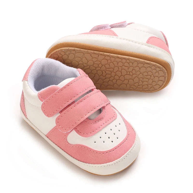 Pink and white soft sole baby pre-walker sneakers for infants shown from the side.