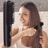 A woman is using a black ionic hair straightening brush on her long brown hair.