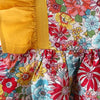 A close-up of a baby girl's floral print dress featuring yellow puff sleeves and a matching hat.