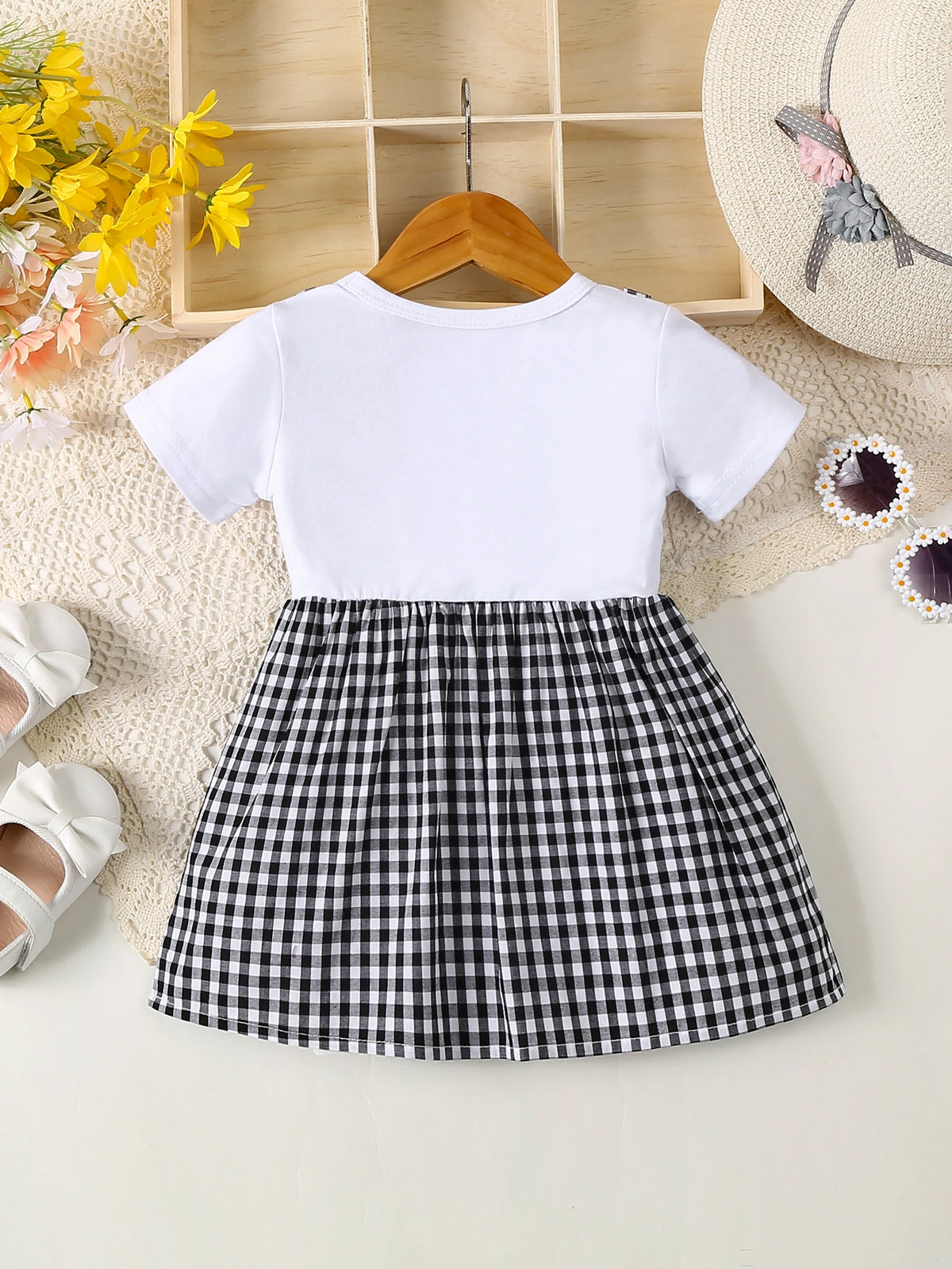 A white short-sleeved cotton knit dress with a black and white plaid skirt, displayed on a light background.