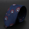 Corbata jacquard azul oscuro con patrón repetido de hojas estilizadas y círculos.