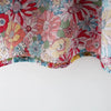 Close-up of a baby girl's floral print dress featuring pink, red, and green flowers.