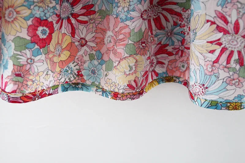 Close-up of a baby girl's floral print dress featuring pink, red, and green flowers.