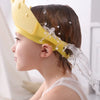 A young child is shown wearing a yellow silicone shampoo crown while being washed in the bath.