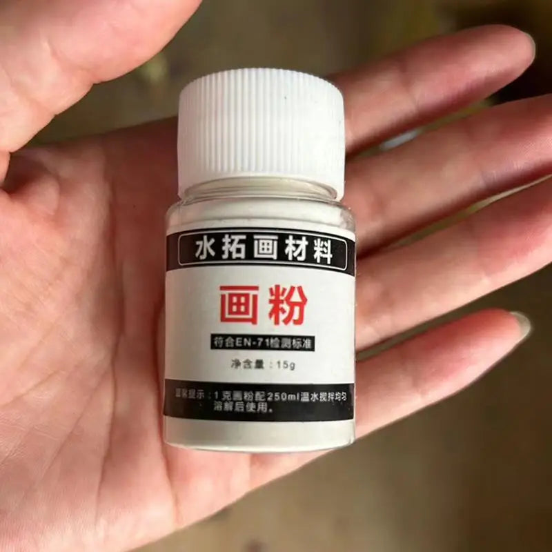 A small white bottle of water marbling paint kit labeled in Chinese characters is held in a person's hand.