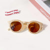 A pair of kids polarized sunglasses with an orange-tinted lens and a light yellow plaid frame resting on a white surface.