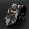 Primer plano de una corbata de hombre con estampado de camuflaje enrollada sobre un fondo oscuro.