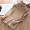 A beige knit turtleneck sweater for kids displayed on a wooden surface.