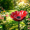 A handcrafted red metal flower garden stake shaped like a flower bowl, set in a sunny garden.