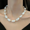 Et vintage geometrisk perlehalskjede med små, uregelmessige hvite perler på en gullfarget kjede.