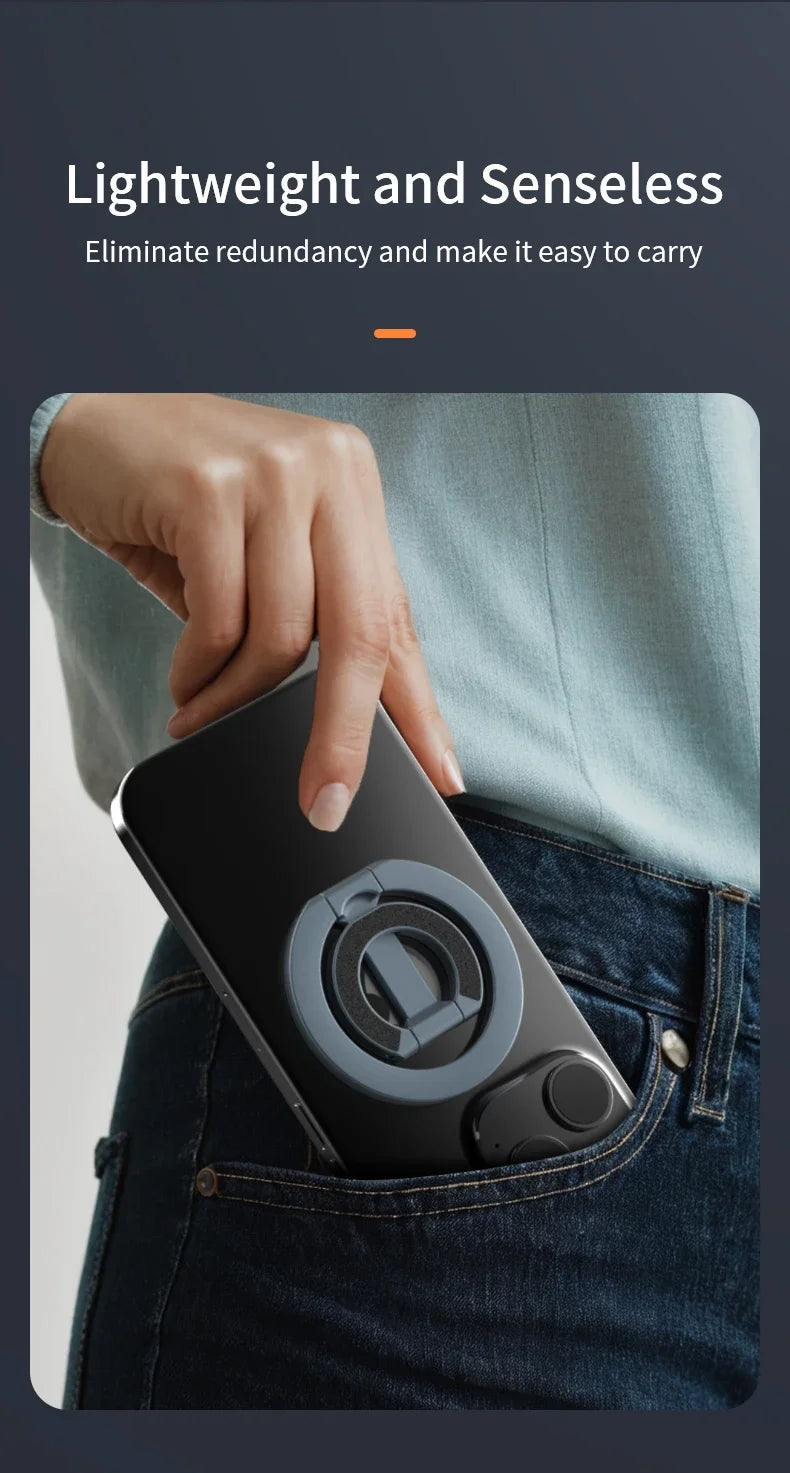 En hånd legger et svart, sammenleggbart magnetisk telefonringstativ i lommen på mørkeblå jeans.