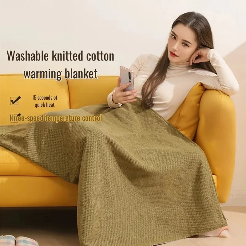 A woman is using a washable knitted cotton warming blanket on a yellow sofa.