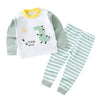 A white and green cartoon dinosaur pajama set for a child with long sleeves and matching striped pants.