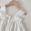 White lace-trimmed vest top and skirt set displayed on a wooden hanger