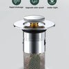 A silver press-type sink drain stopper with a mesh core and a removable lid.