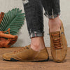 A pair of brown leather men's classic lace-up loafers resting on a wooden surface next to denim jeans.