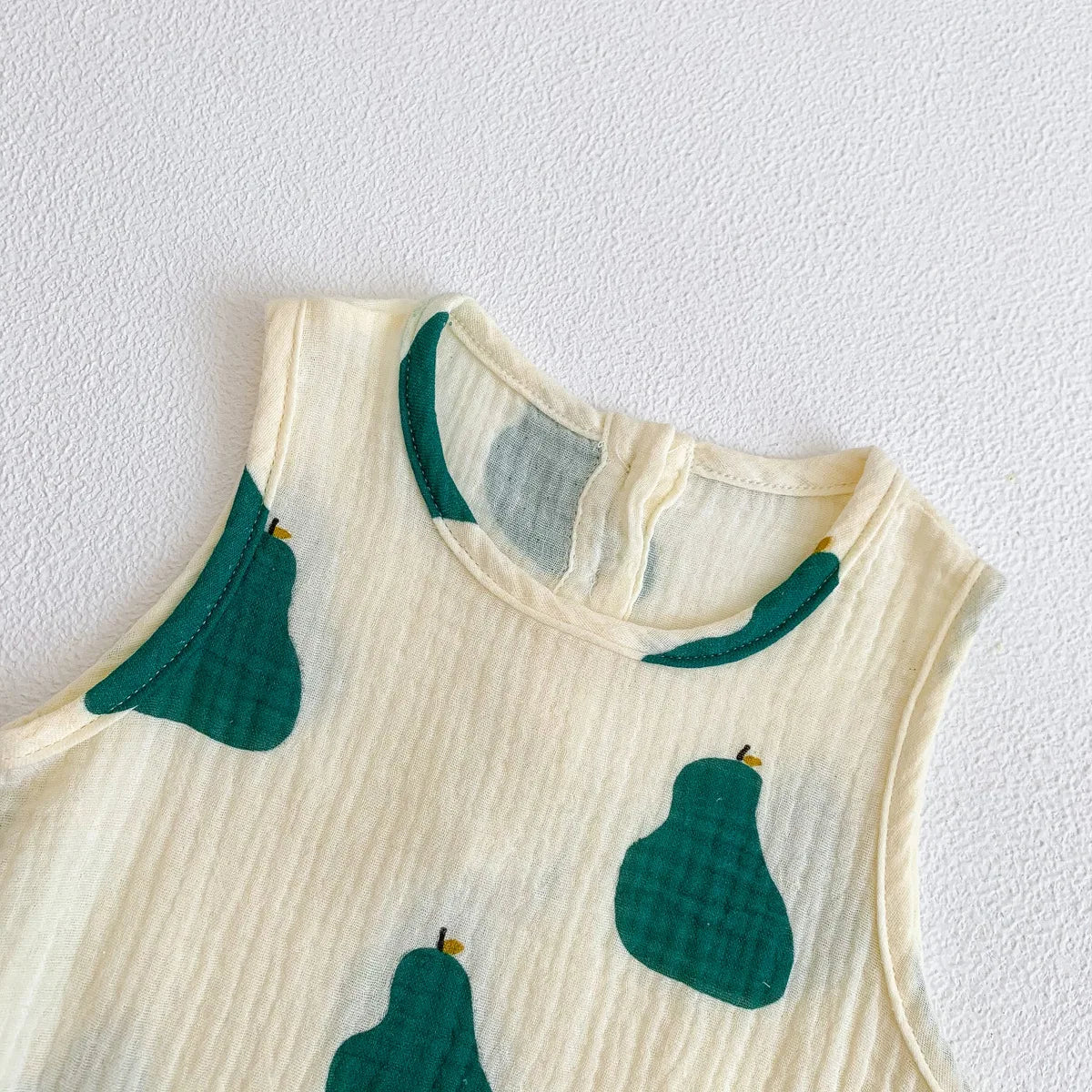 A cream-colored baby cotton sleeveless jumpsuit bodysuit set featuring green pear print details.