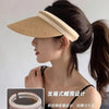 A woman models a woven straw sun hat with a wide brim, styled in an elegant updo.