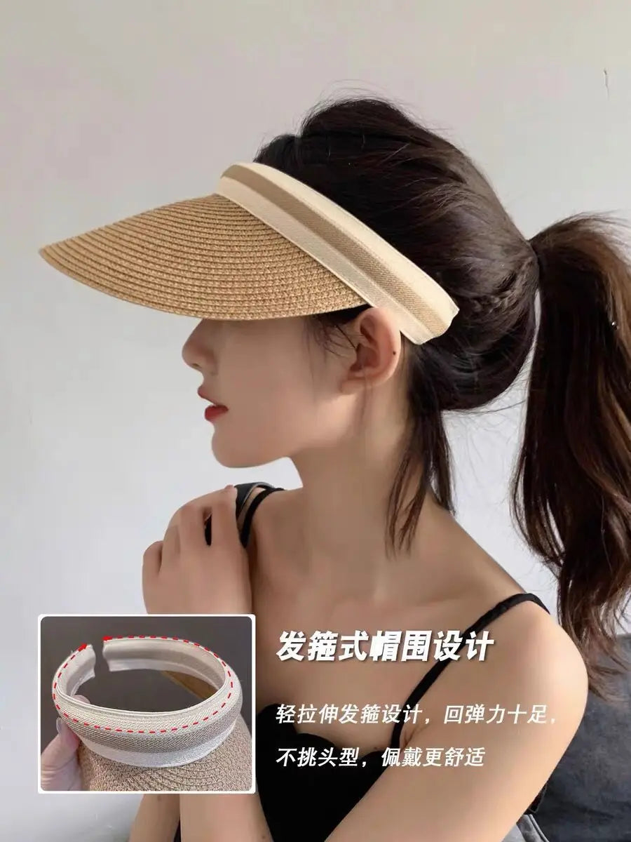 A woman models a woven straw sun hat with a wide brim, styled in an elegant updo.