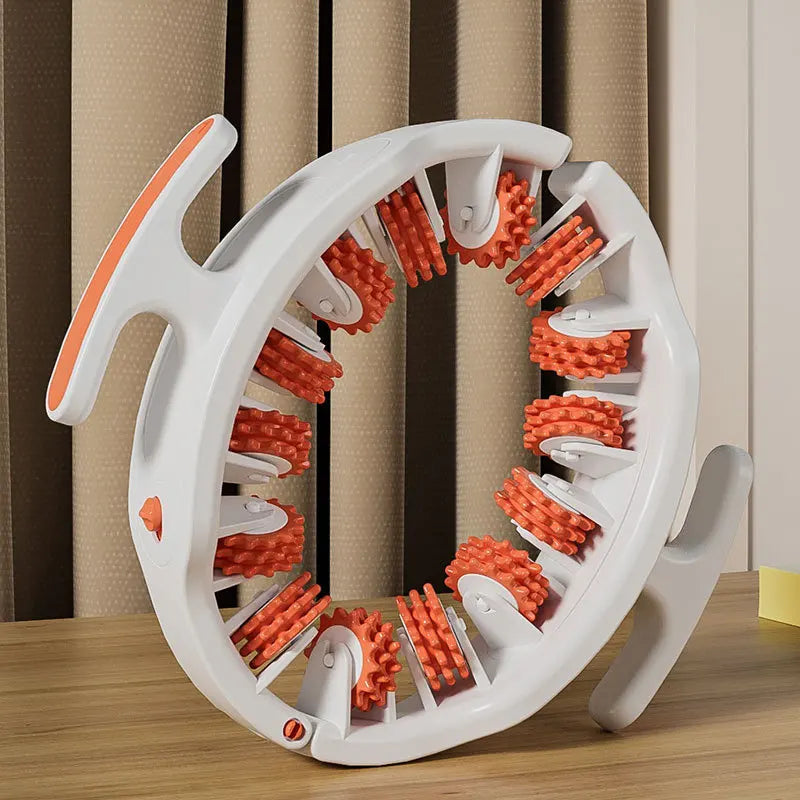 A white full body massage roller with orange handles is shown on a wooden surface.