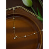 A gold heart pendant necklace with simulated pearls displayed on a brown plate.