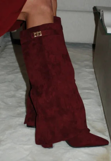A close-up of a maroon knee-high boot with a chunky heel and a gold metal buckle.