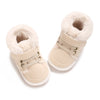 A pair of beige faux fur baby winter snow boots for toddlers with light tan fabric and white soles.