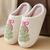 Pair of white fuzzy winter slippers decorated with pink and green Christmas trees
