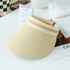 A woven straw sun hat with a light beige brim and band resting on a white surface.
