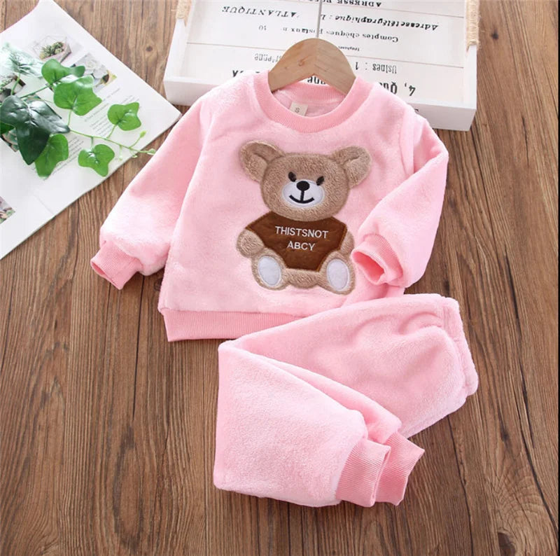 Pink fleece pajama set for a child featuring a teddy bear design and matching pants.