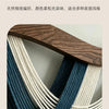Handwoven macrame tapestry with blue and white threads wrapped around a wooden rod.