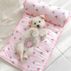 A fluffy white puppy is lying on a pink ice silk pet cooling mat with small fruit patterns.
