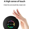 A hand is holding a black compact waterproof Bluetooth speaker with a suction cup mount.